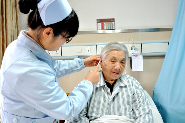 图为该院护士为患者进行耳穴埋豆治疗